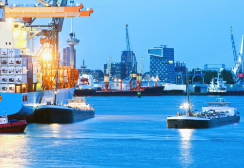 Rotterdam. A busy seaport with intense blue saturated color. Boats are on the water, and the city of Rotterdam is viewable in the background.