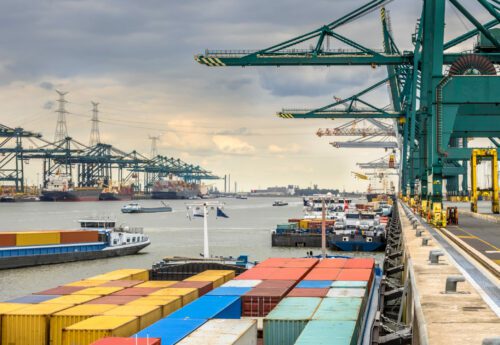 Loaded ships in busy port of Antwerp at container terminal with automated cranes and lots of vessels. Belgium