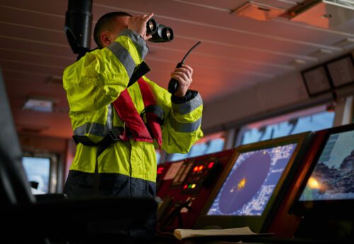 Navigator. pilot, captain as part of ship crew performing daily duties with VHF radio, binoculars, logbook, standing nearby to ECDIS and radar station on board of modern ship with high quality navigation equipment on the bridge. Great design for navigation, safety of shipping, cargo carriage purposes