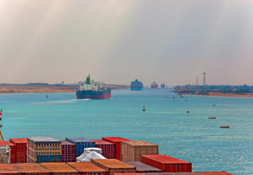 Industrial container ship passing through Suez Canal with ship s convoy, view on the bow from the captain bridge.