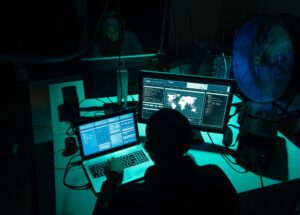 Wanted hackers coding virus ransomware using laptops and computers in the basement. Cyber attack, system breaking and malware concept.