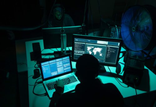 Wanted hackers coding virus ransomware using laptops and computers in the basement. Cyber attack, system breaking and malware concept.