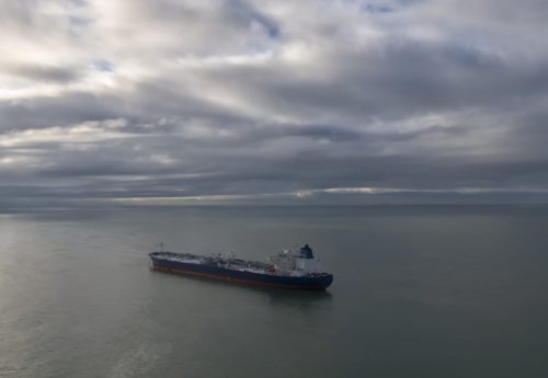 Aerial drone photo from drone of a suezmax tanker at anchor in cloudy weather.