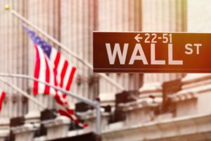 Wall street sign with the New York Stock Exchange on the background at sunset