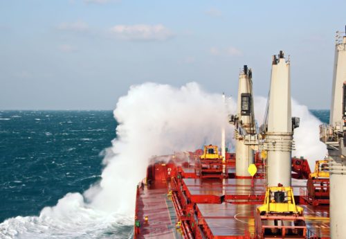 Movement of the vessel in stormy weather, Pacific Ocean. Waves and spray covering the ship during a storm