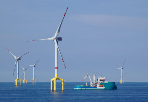 Offshore wind turbine with supply boat in the north sea with blue sky and sea