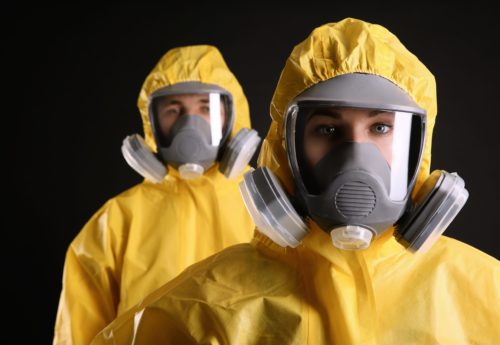 Man and women wearing chemical protective suits on black background. Virus research