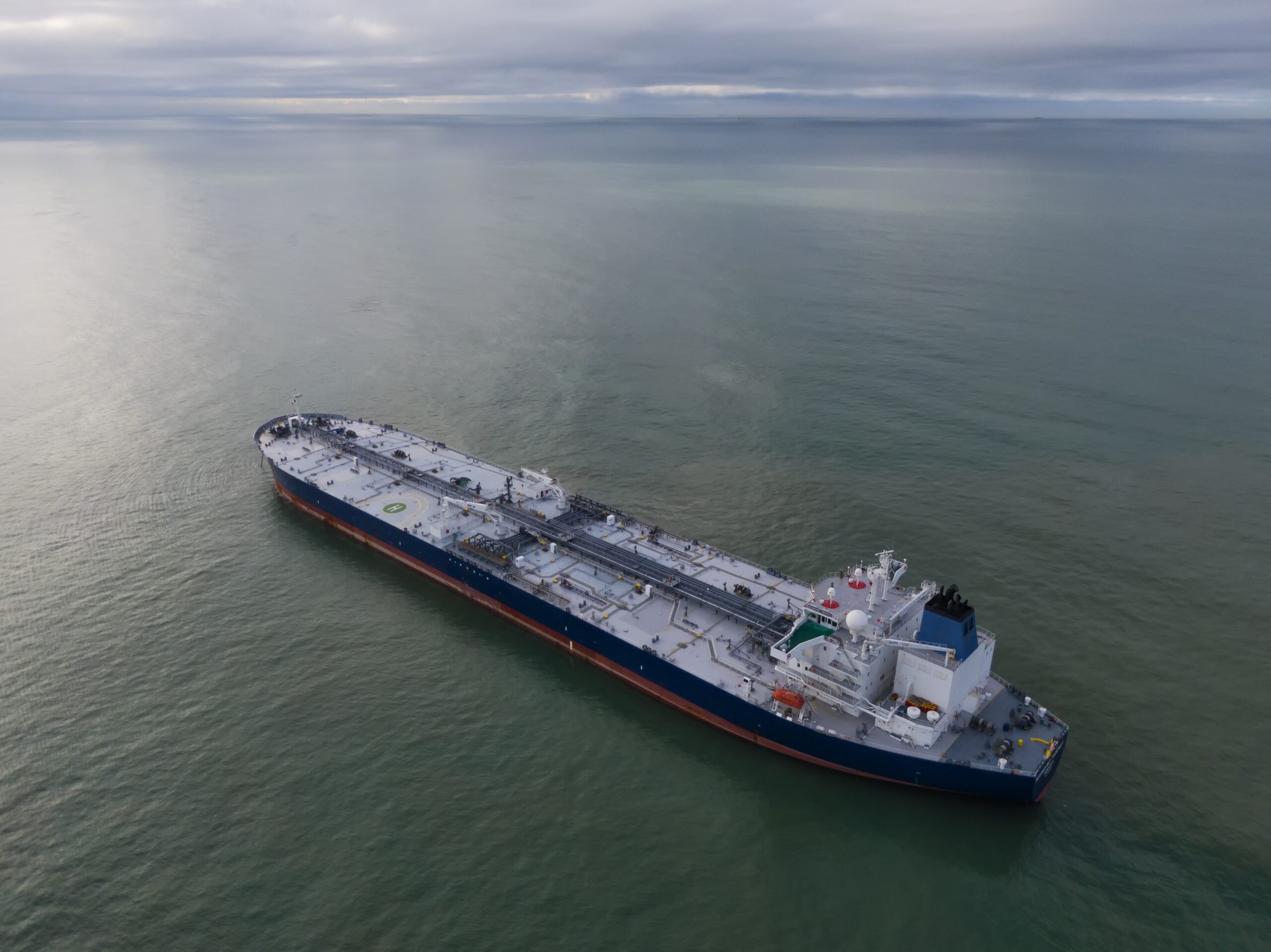 Aerial drone photo from drone of a suezmax tanker at anchor in cloudy weather.