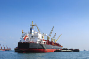 Supramax vessel loading cargo at anchorage from barges alongside