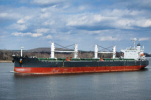 Empty Supramax bulk carrier with deck cranes sailing on a river calm water