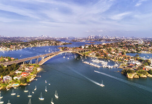 Gladesville bridge across Parramatta river in Sydney`s Inner West with distant view of the city CBD on the horizon.