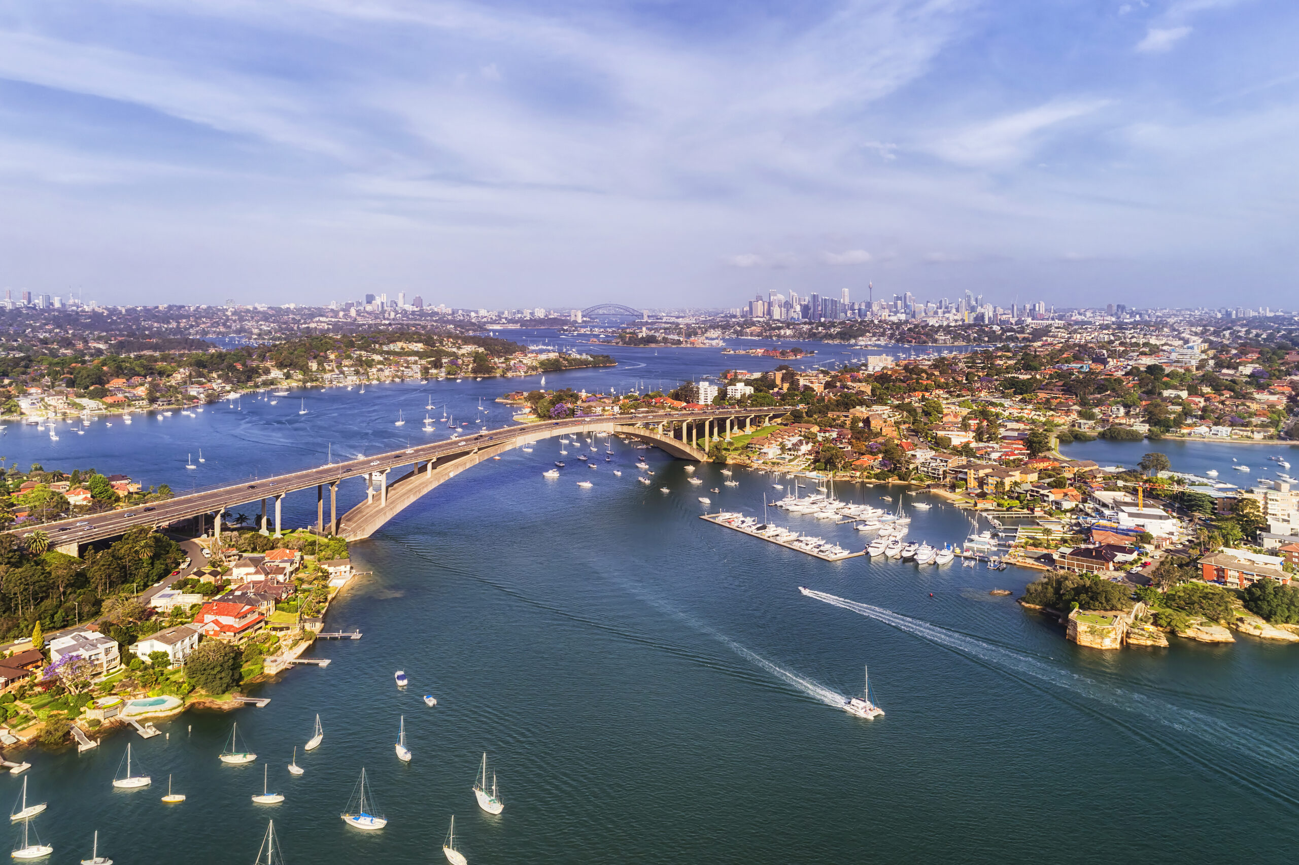 Gladesville bridge across Parramatta river in Sydney`s Inner West with distant view of the city CBD on the horizon.