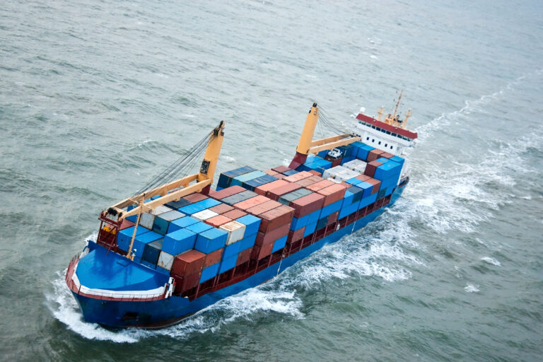 A fully loaded cargo container ship underway in full speed.