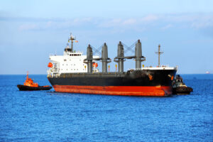 Two tugboats assisting Supramax to harbor quayside