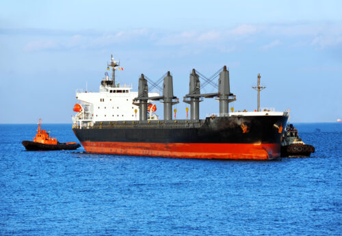 Two tugboats assisting Supramax to harbor quayside