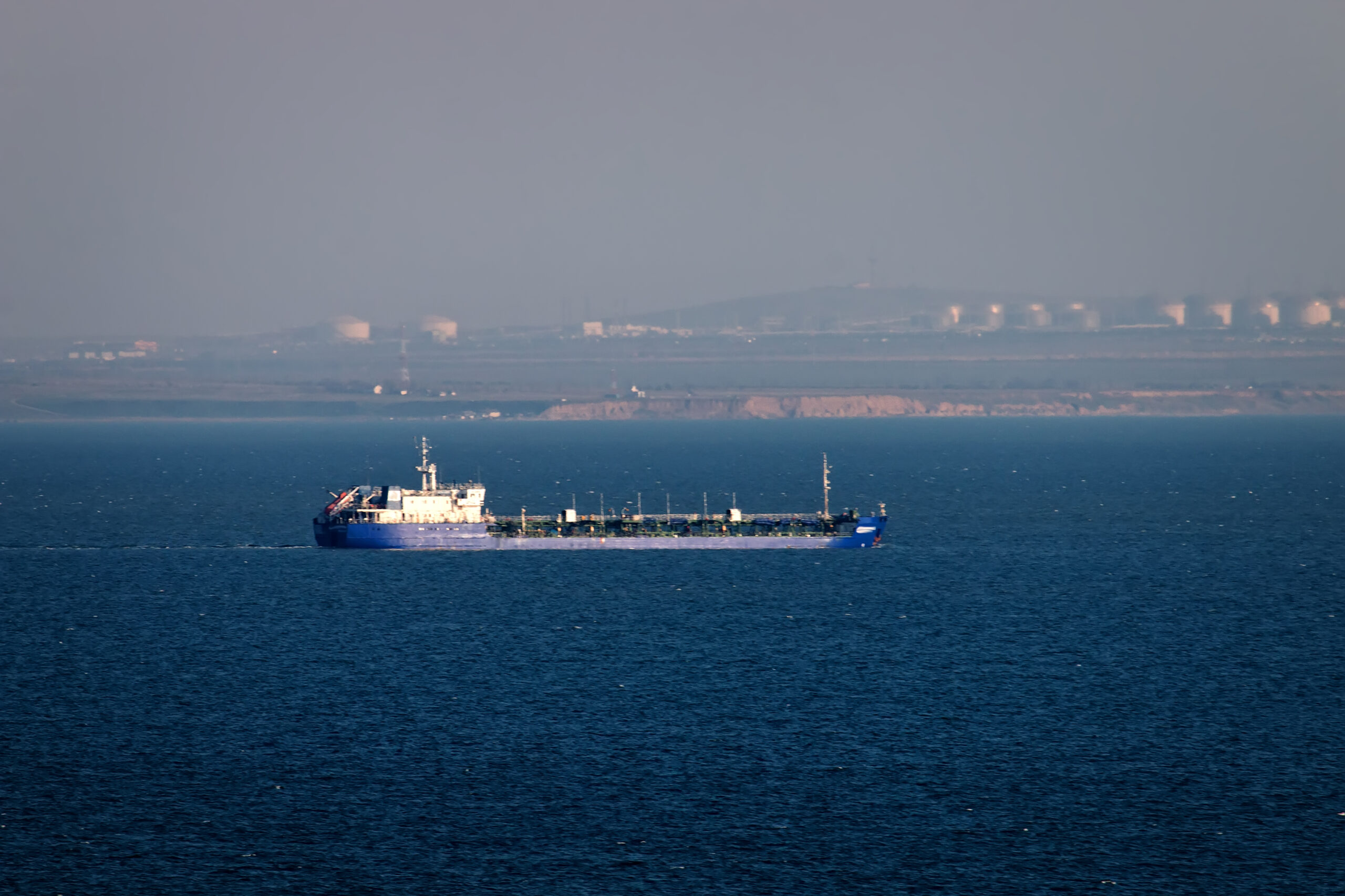 Shipping in Kerch Strait of Black sea of Azov sea. Oil tanker river-sea and huge tanks with fuel on shore Taman, ship traffic, cabotage. Marine transportation of petroleum products, oil terminal