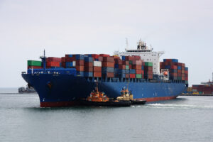 Tugboats pulling a container vessel in sea port area
