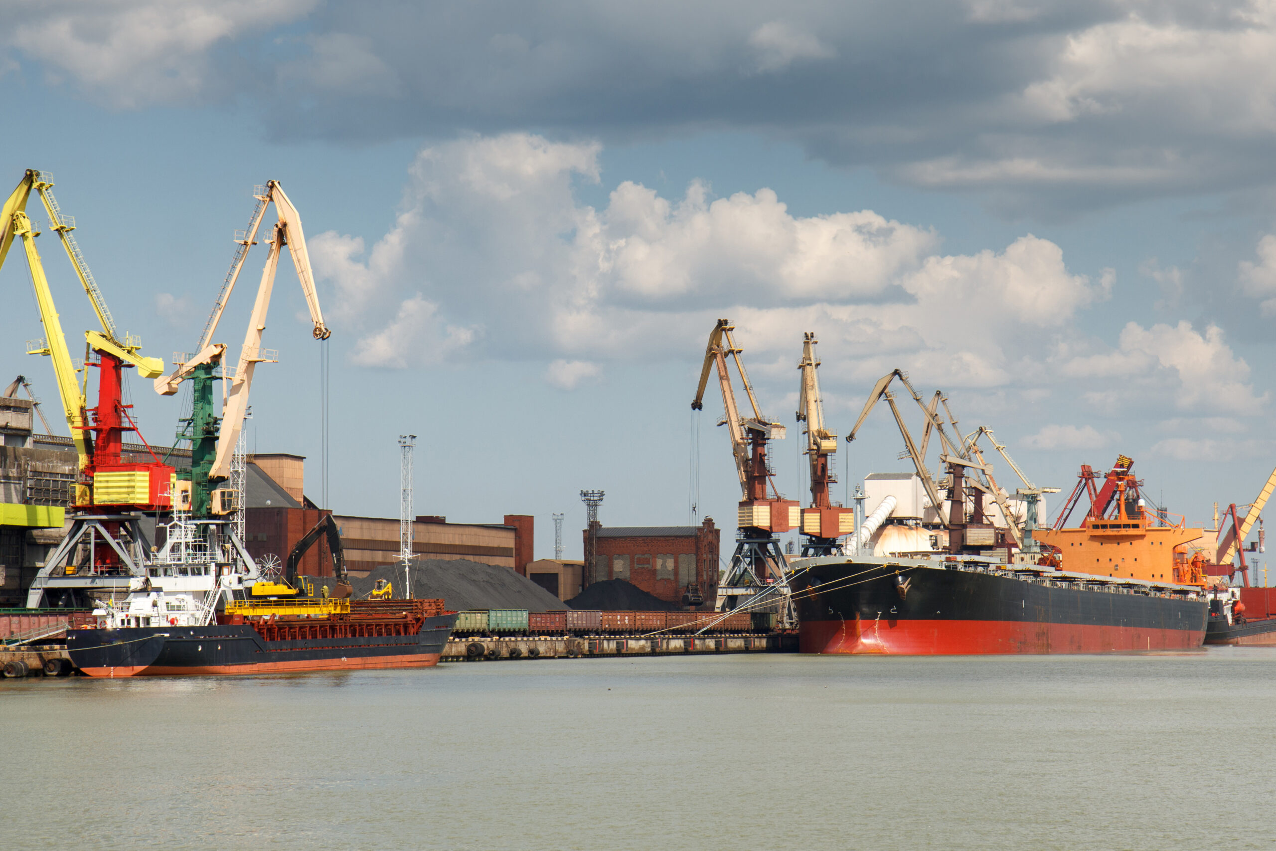 Industrial harbor with two freight ships with coal being loaded in.