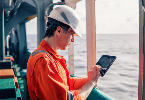 Chief officer or captain on deck of vessel or ship watching digital tablet