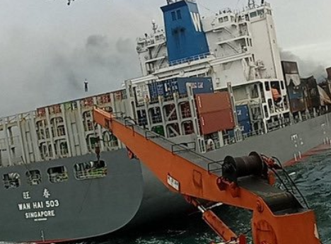 Fire-stricken Wan Hai 503 boxship under tow by salvage tugs.